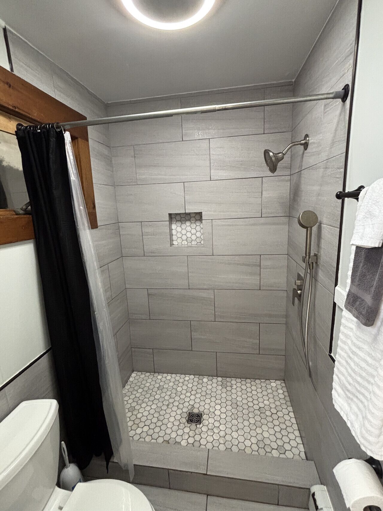 A shower area with a tiled floor, a showerhead, and a curtain.