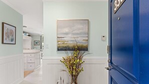 A hallway with a blue door labeled "330", a painting of a landscape, and a vase with flowers.
