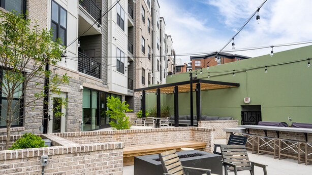 Un patio al aire libre con asientos, una fogata y una pared verde.