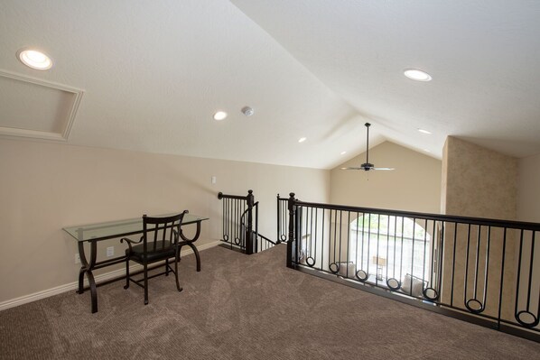 A spacious room with a dining table and chairs, a staircase with a railing, and a ceiling fan.