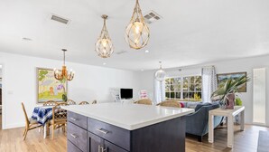 A spacious kitchen with a large island, pendant lighting, and a dining area with wicker chairs. - Tequesta/Jupiter Pool Home close to Beaches and Dining. 2 miles to the beach. (Tequesta)