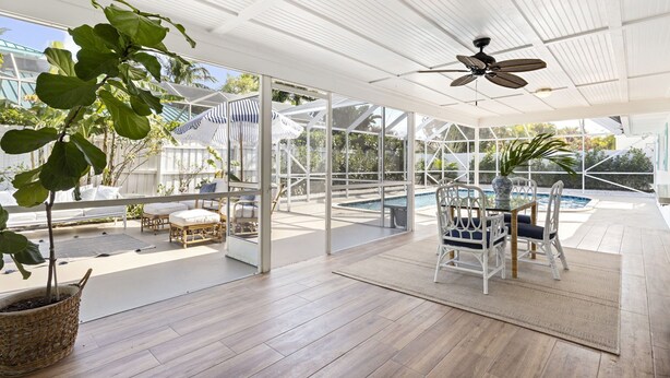 An indoor patio with a pool, wicker furniture, and a ceiling fan. - Tequesta/Jupiter Pool Home close to Beaches and Dining. 2 miles to the beach. (Tequesta)