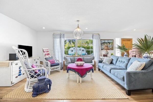 A living room with a sofa, armchairs, a coffee table, and a TV.