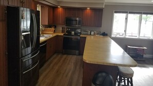 A kitchen with wooden cabinets, a black refrigerator, a microwave, a stove, and a wooden countertop. - Chalet Ripple-Lake Harmony- Lakefront- 5 Bedroom 3.5 bath- near Restaurants/Bars (Lake Harmony)