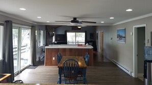 A spacious kitchen with a central island, wooden dining table, and blue chairs. - Chalet Ripple-Lake Harmony- Lakefront- 5 Bedroom 3.5 bath- near Restaurants/Bars (Lake Harmony)