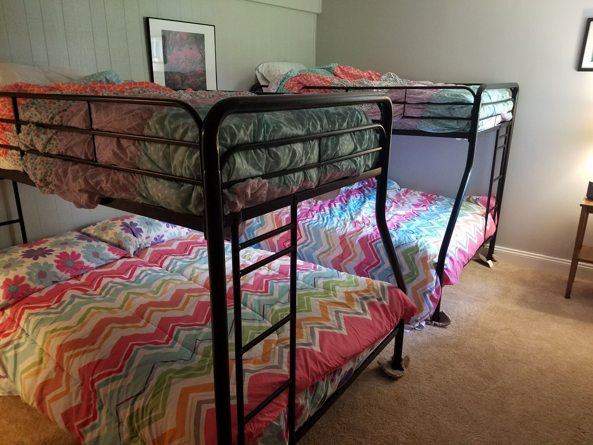 A room with bunk beds, each with colorful bedding.