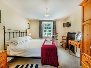 A neatly arranged bedroom with a bed, a desk, a chair, a television, and a window with curtains. - 2 bedroom accommodation in Rumleigh (Rumleigh)