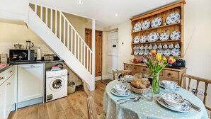 A kitchen with a microwave, washing machine, and a dining area with a table set for two.