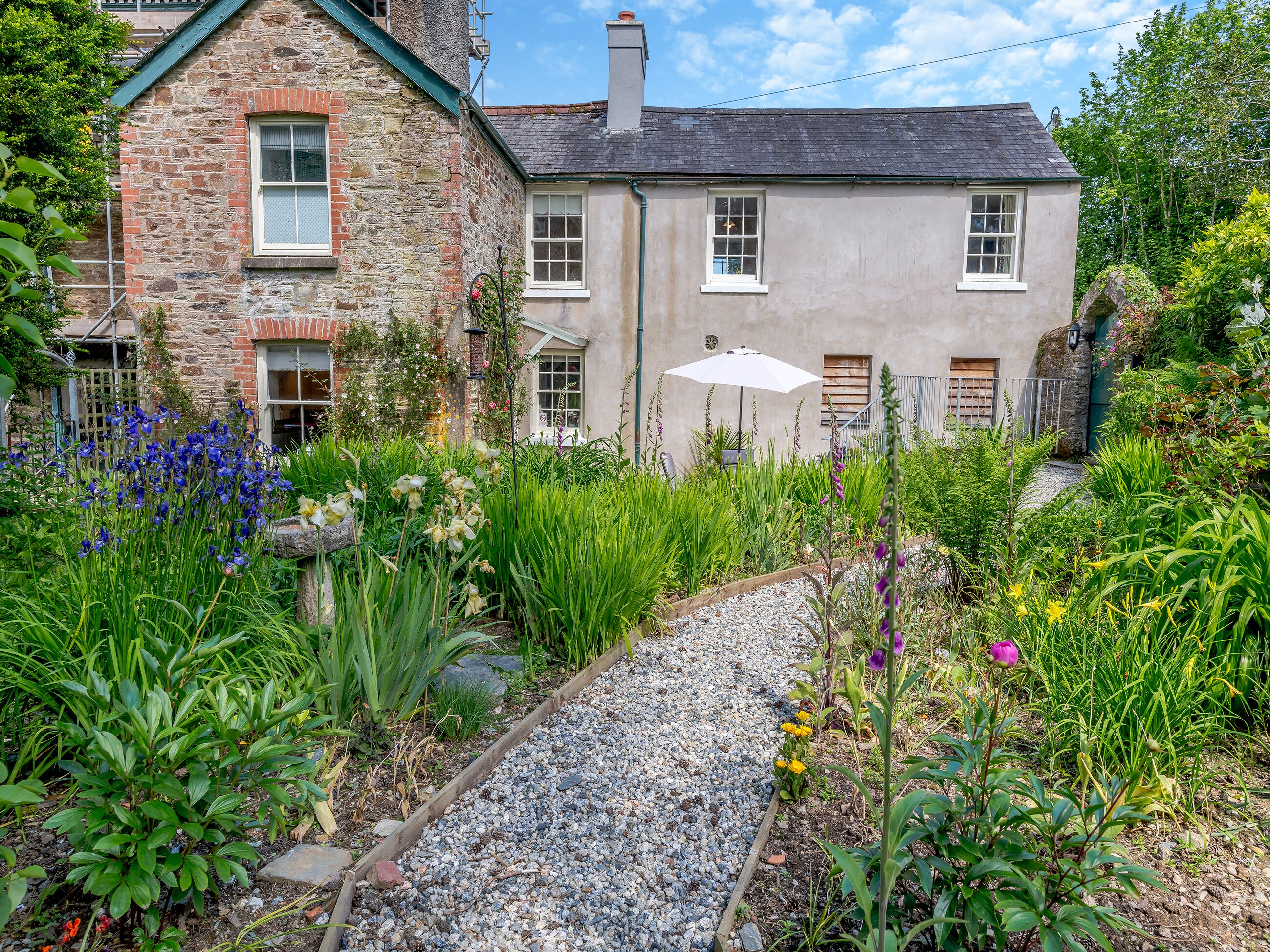 A stone and plaster house with a gravel pathway leading to a wooden door.