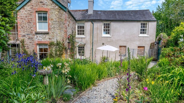 A stone and plaster house with a gravel pathway leading to a wooden door.