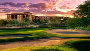 Campo de golf con búnkeres y un edificio de varios pisos al fondo.