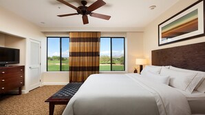Habitación de hotel con cama, televisión, escritorio y ventana con vista a un campo de golf.
