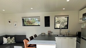 Una cocina moderna con una isla central, armarios blancos y un rincón de comedor con un sofá gris y sillas marrones.
