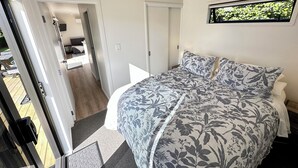 Un dormitorio con una cama grande, una puerta que da a un balcón y vistas a un jardín.