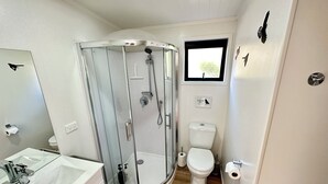 Un baño compacto con ducha de vidrio, inodoro y lavamanos con espejo.