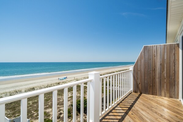 A wooden deck with a white railing overlooking a beach. - Oceanfront stunner in Emerald Isle (Emerald Isle)