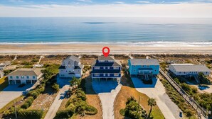 An aerial view of a coastal residential area with houses, a beach, and a clear sky. - Oceanfront stunner in Emerald Isle (Emerald Isle)