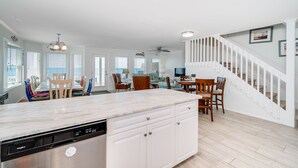 A spacious kitchen with a central island, white cabinetry, and a dishwasher. - Oceanfront stunner in Emerald Isle (Emerald Isle)