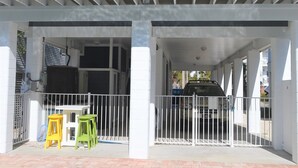 Ein zweistöckiges Gebäude mit überdachter Balkon und einem Pool davor.