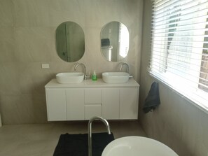A bathroom with two sinks, a mirror, and a window with blinds. - Spacious ocean view beach house - sleeps 12 (Smiths Beach)
