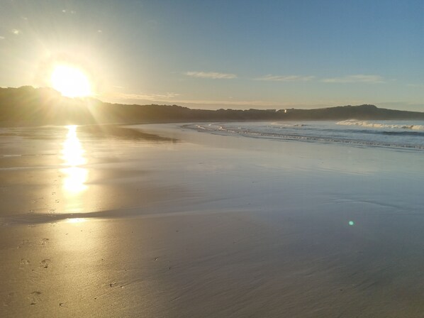 A beach with a clear sky and the sun reflecting on the wet sand. - Spacious ocean view beach house - sleeps 12 (Smiths Beach)