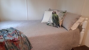 A bed with a floral blanket, a green bird pillow, and a patterned pillow. - Experience a unique part of Australian History (Nagambie)