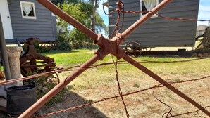 A rustic outdoor setting with a metal structure, possibly a fence or gate, in a yard with a house in the background. - Experience a unique part of Australian History (Nagambie)