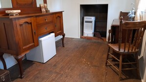 A room with a wooden dresser, a white refrigerator, a wooden chair, and a fireplace. - Experience a unique part of Australian History (Nagambie)