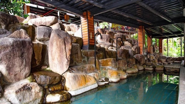 A pool with large rocks and a covered area with chairs. - North Mountain Farm (Puli)