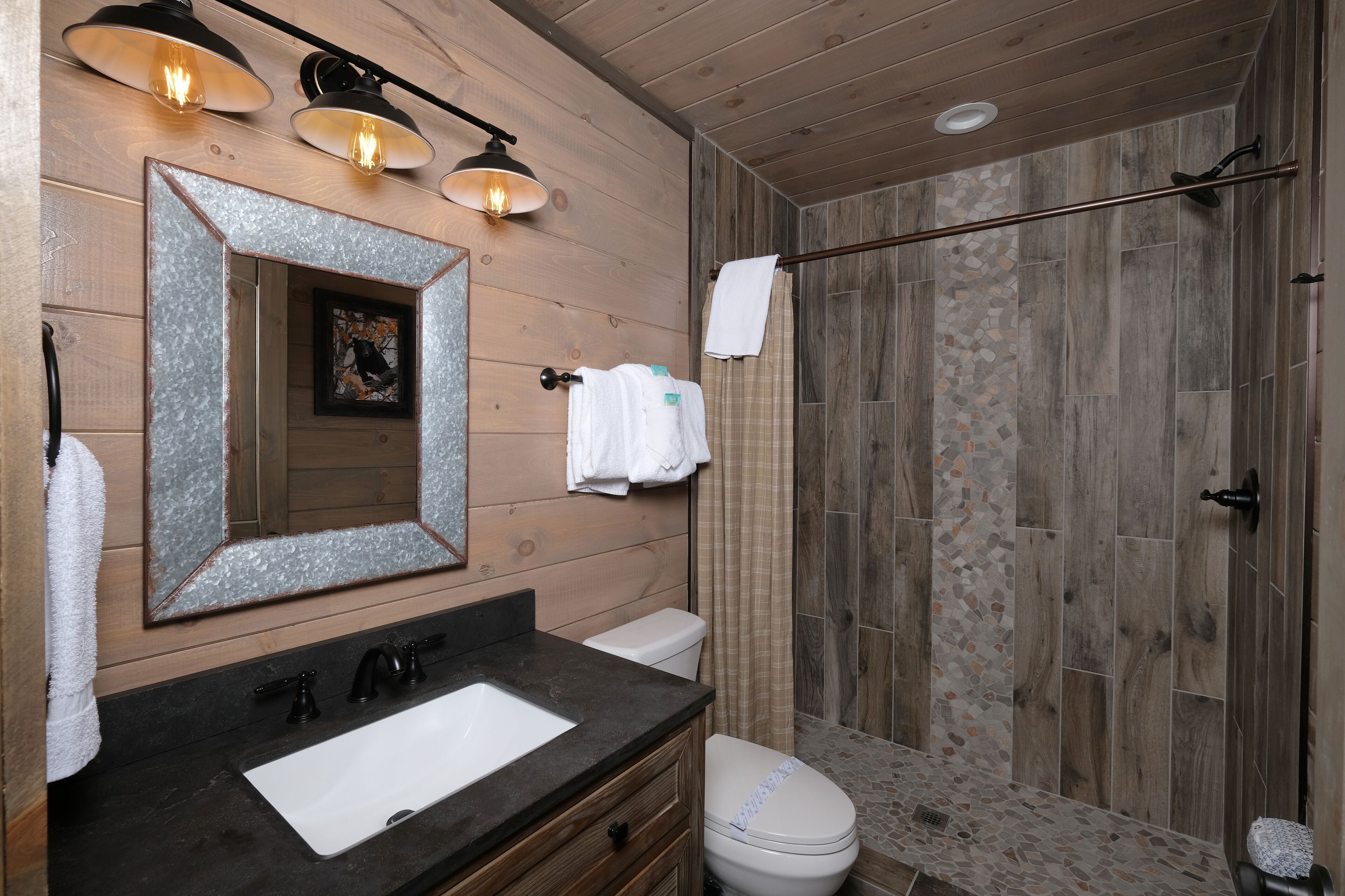 A bathroom with a wooden interior, a sink, a toilet, and a shower area.
