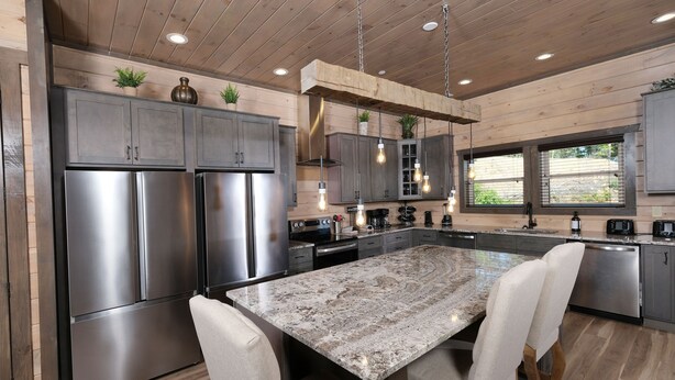 A modern kitchen with stainless steel appliances, a granite countertop, and wooden cabinetry. - Hibernation Hideaway - Private indoor pool, theater room, hot tub, games, and more! (Pigeon Forge)