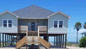 A two-story house with a front porch and wooden stairs leading to the entrance. - Agua de copano (Rockport)
