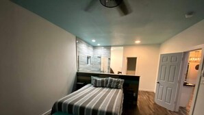 A compact bedroom with a bed, bench, and a mirror. - Agua de copano (Rockport)