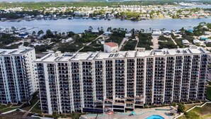 A high-rise hotel with multiple balconies, a swimming pool, and a marina in the background. - Extra Large Balcony Phoenix VII 3/2 Flash Sale (Orange Beach)