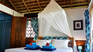 A bed with a canopy, blue and white pillows, and folded towels. - Premium Suite, lagoon view, 2 bedrooms, kitchen, bathroom (Moorea)