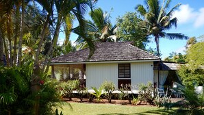 A white building with a tiled roof, surrounded by lush greenery and palm trees. - Premium Suite, lagoon view, 2 bedrooms, kitchen, bathroom (Moorea)