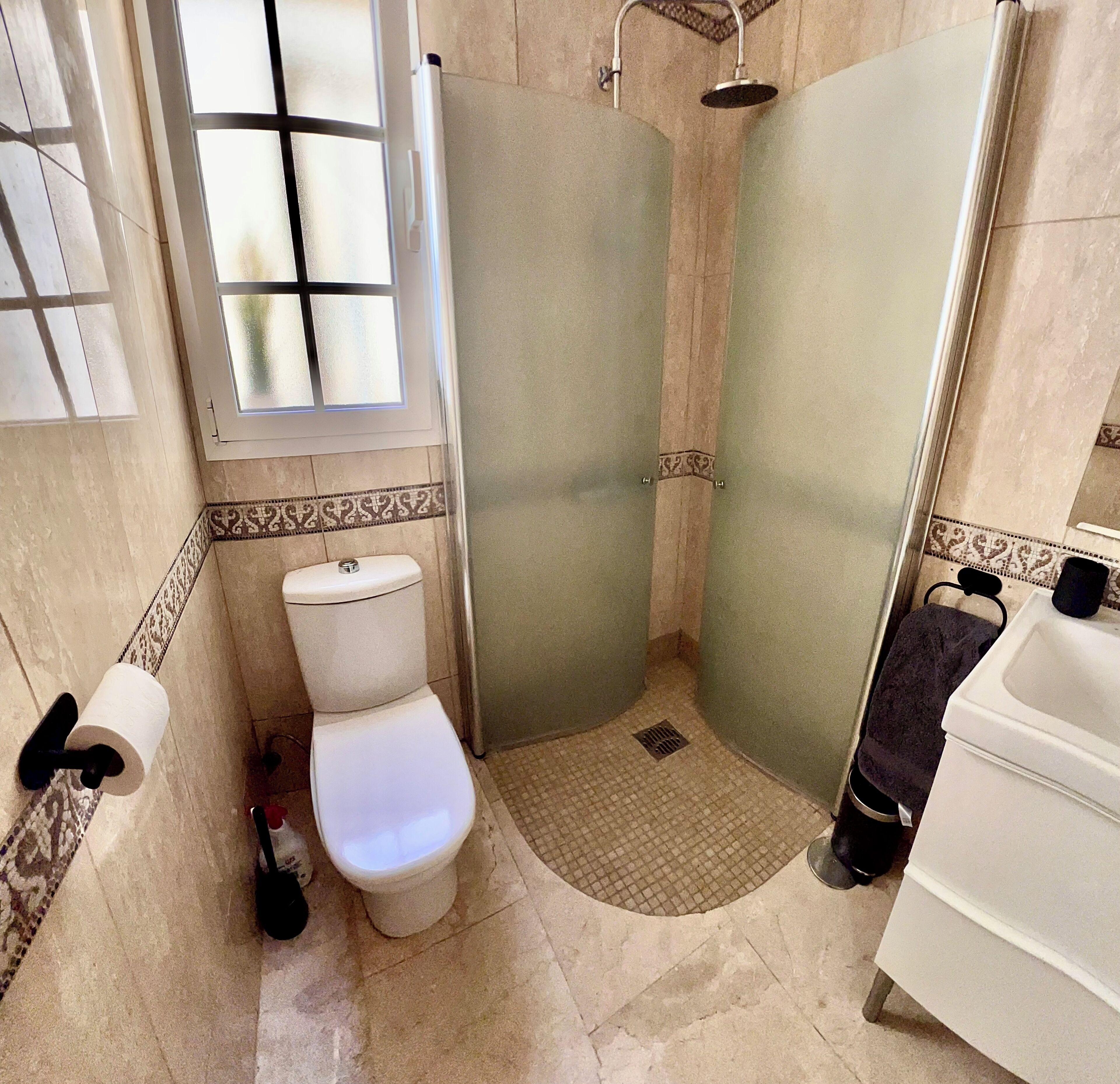 Une salle de bain avec des toilettes, une douche et un lavabo.