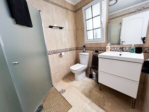 A bathroom with a toilet, sink, and mirror. - Beautiful Two bedroom apartment with spacious terrace, swimming pool and WIFI (Puerto de Mogan)