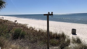 Una playa con un poste de madera y un bote de basura.