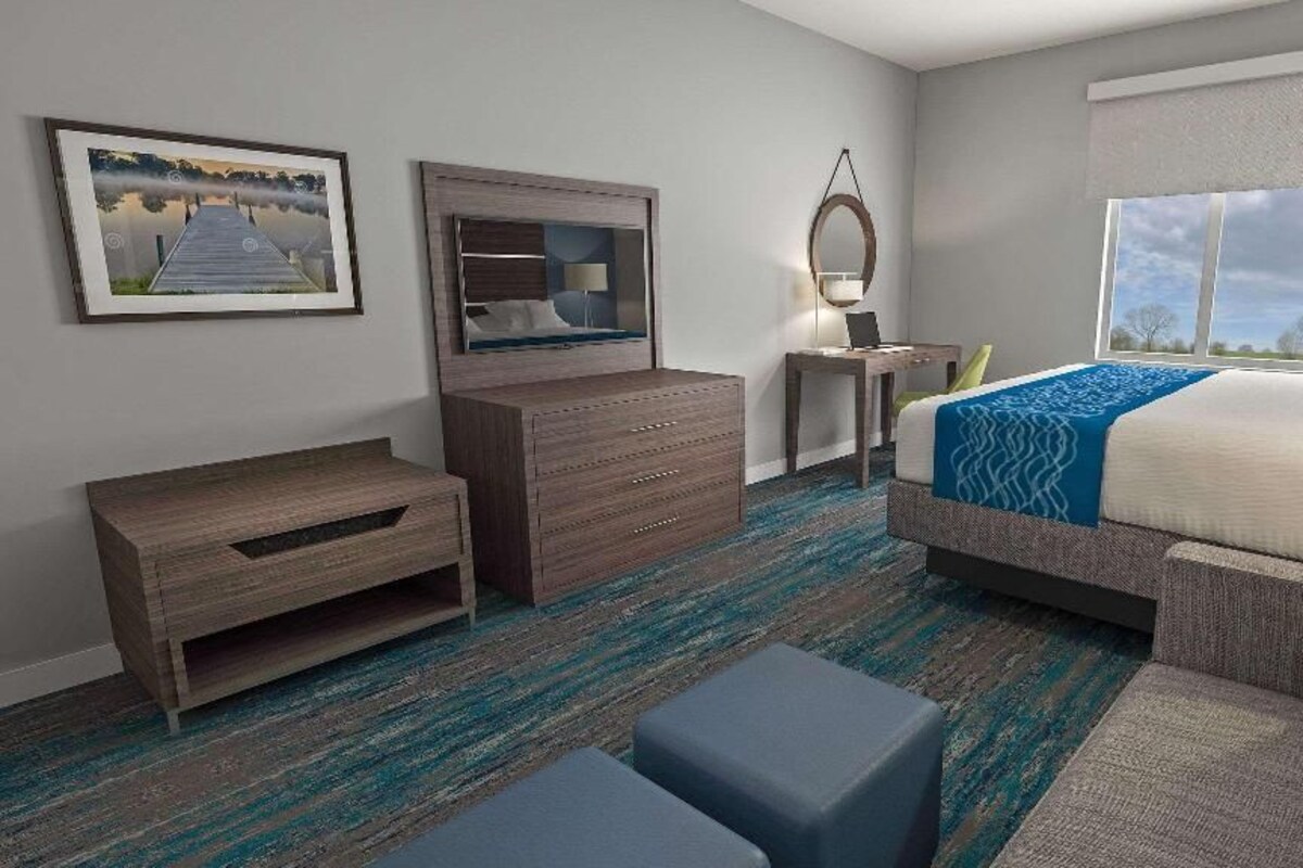 A hotel room with a bed, a desk, a dresser, a mirror, and a window.