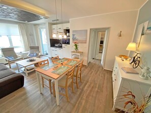 Uma sala de estar moderna com área de refeições, cozinha e vista para o exterior.