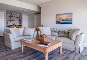 A living room with two sofas, a coffee table, and a painting of a boat on water.
