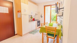 Eine kompakte Küchenzeile mit Essbereich, ausgestattet mit einem Herd, einer Spüle und einem kleinen Kühlschrank.
