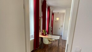 A hallway with wooden flooring leading to a dining area with a table and chairs. - Excellently located 2-room apartment with balcony and high-speed internet in Mitte (Berlin)