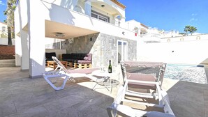 Une villa moderne dotée d’un mur en pierre, d’une piscine et d’un espace salon extérieur.