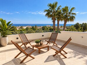 Terraço no telhado com quatro cadeiras de madeira, uma mesa pequena e um vaso de planta.