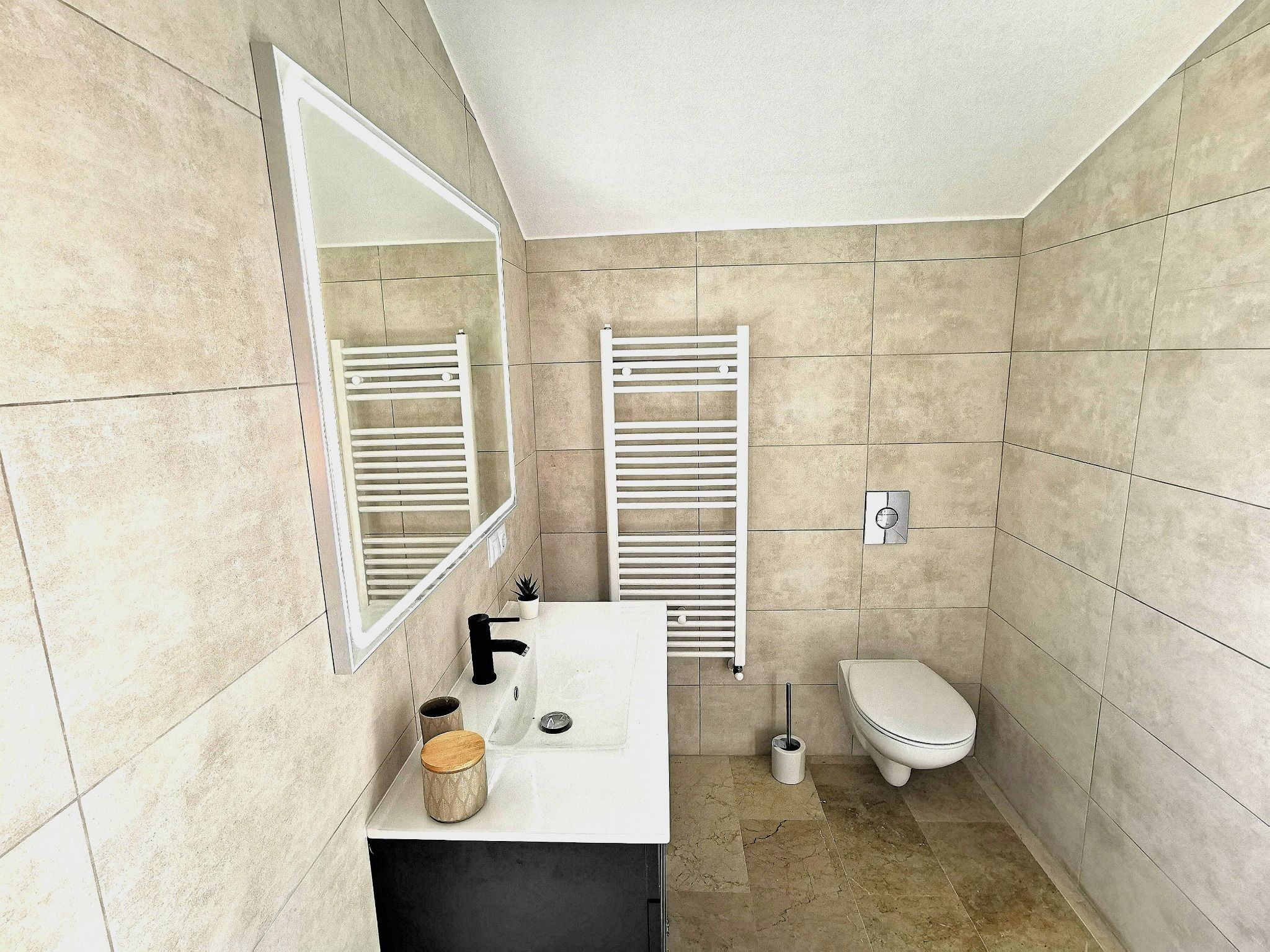 Un bagno con un lavandino bianco, uno specchio, un WC e un portasciugamani.