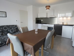 A compact kitchen with a dining area, including a table, chairs, and a sofa. - Comfortable 43m² T2 with terrace and parking in Sète (Sète)