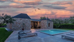 Ein Steinhhaus mit Pool, Gartenmöbeln und einer Terrassenfläche.