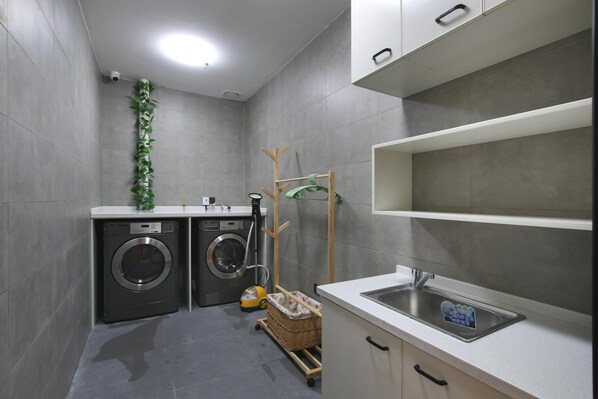 A laundry area with a washing machine, dryer, and a drying rack. - Hanting Hotel (Zhenjiang)